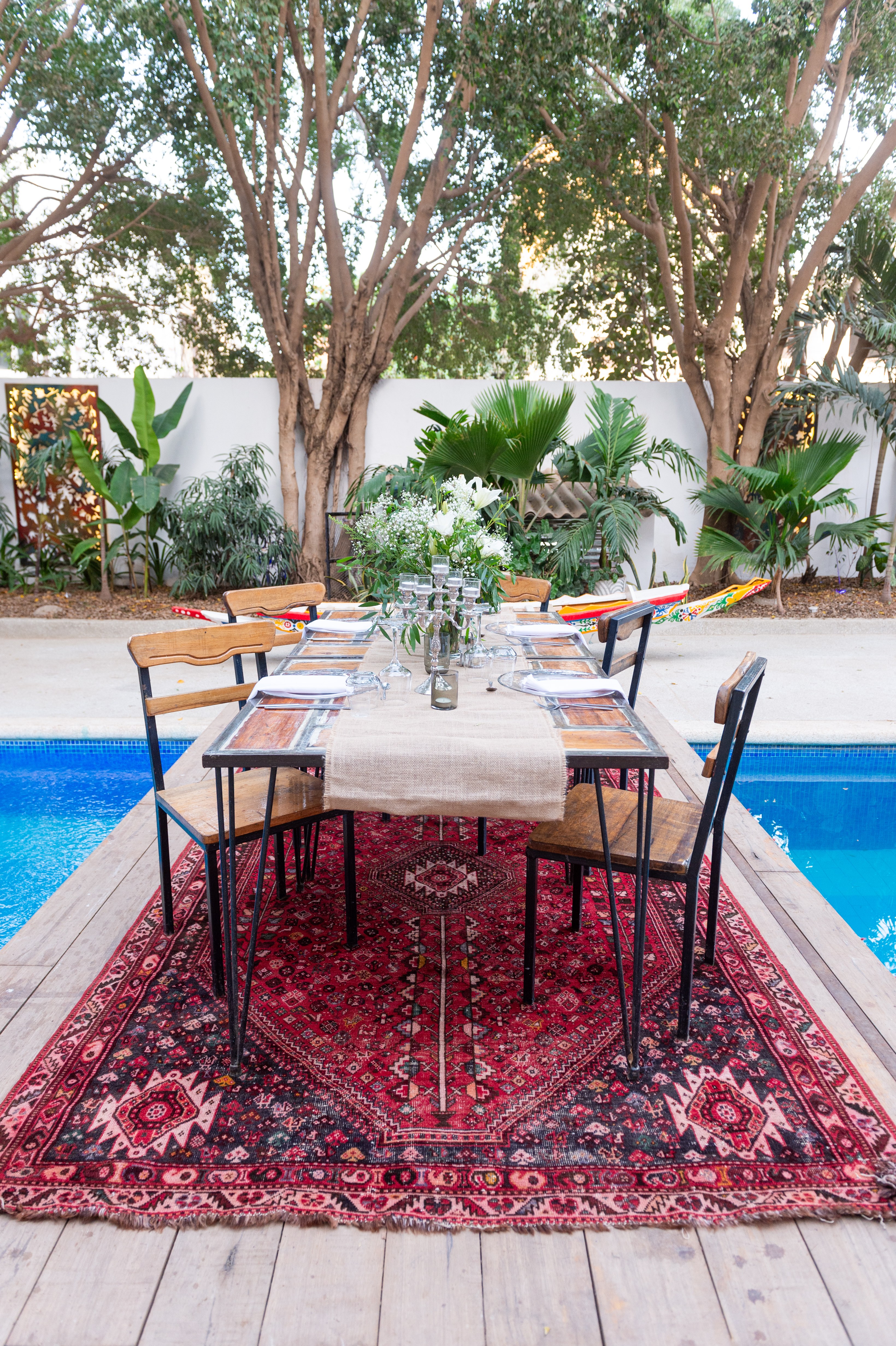 Table dressée au bord de la piscine, à l’ombre des arbres